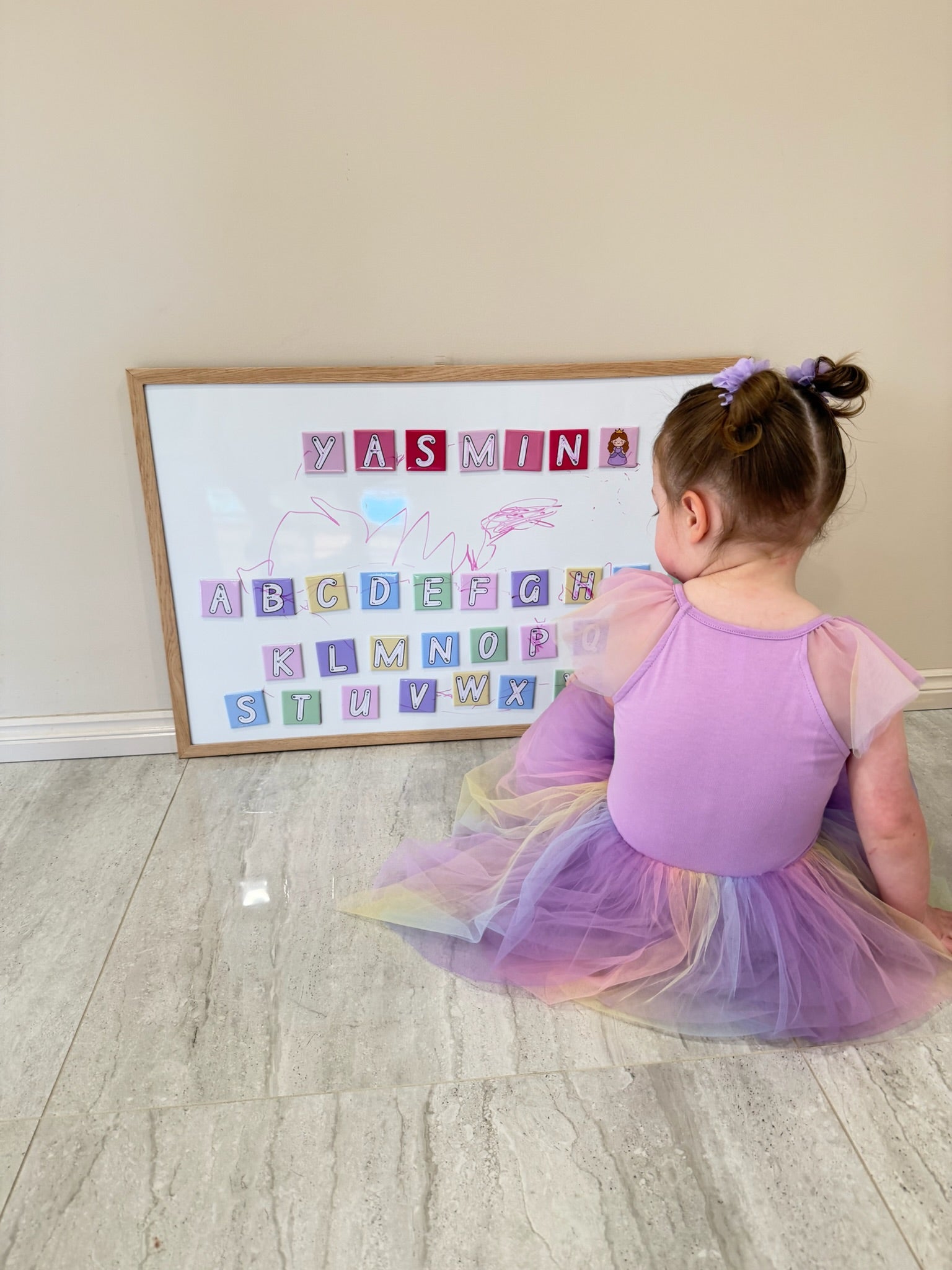 young girl practicing her alphabet writing with Write & Wipe educational alphabet magnets
