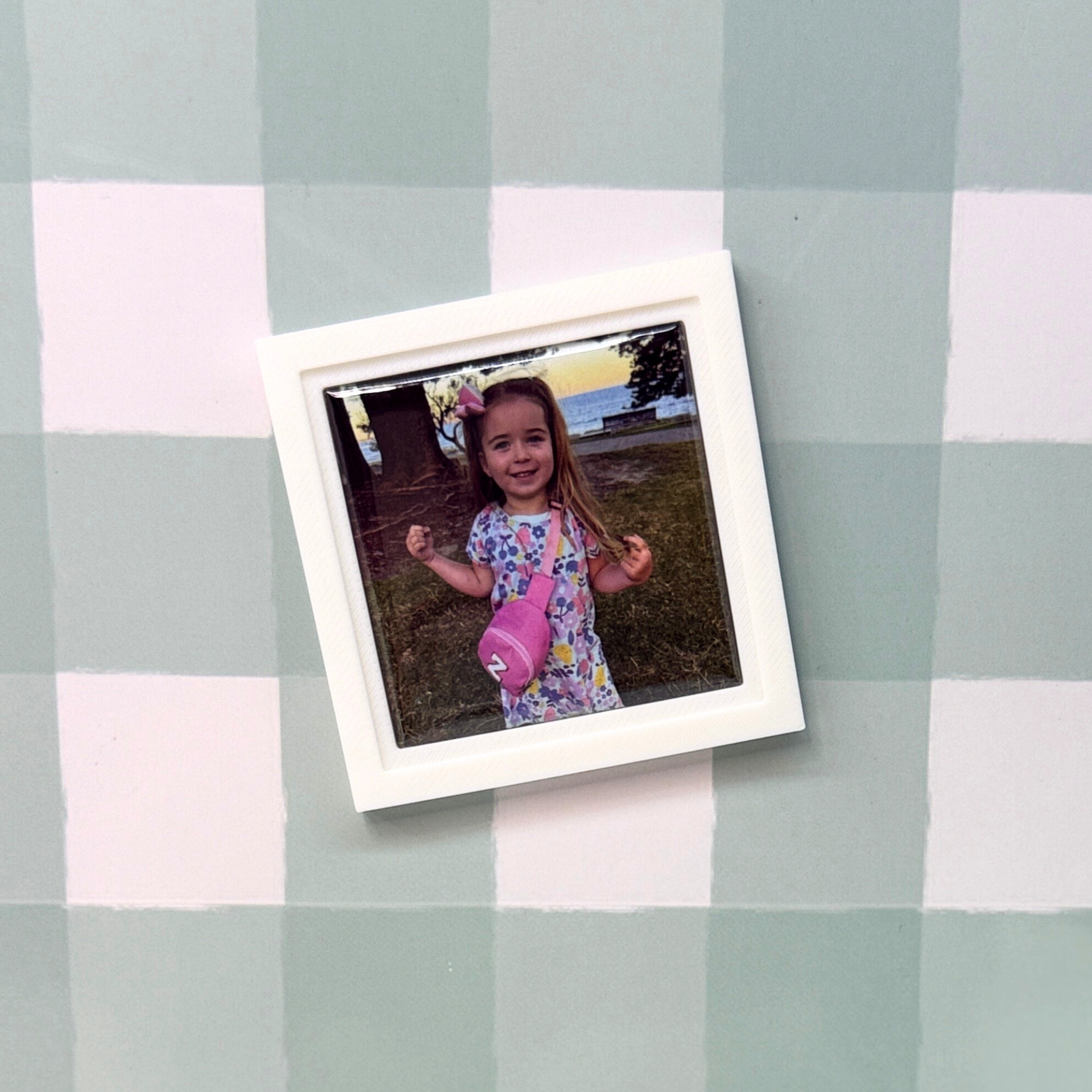 Polaroid photo of a young girl on a checkered tablecloth