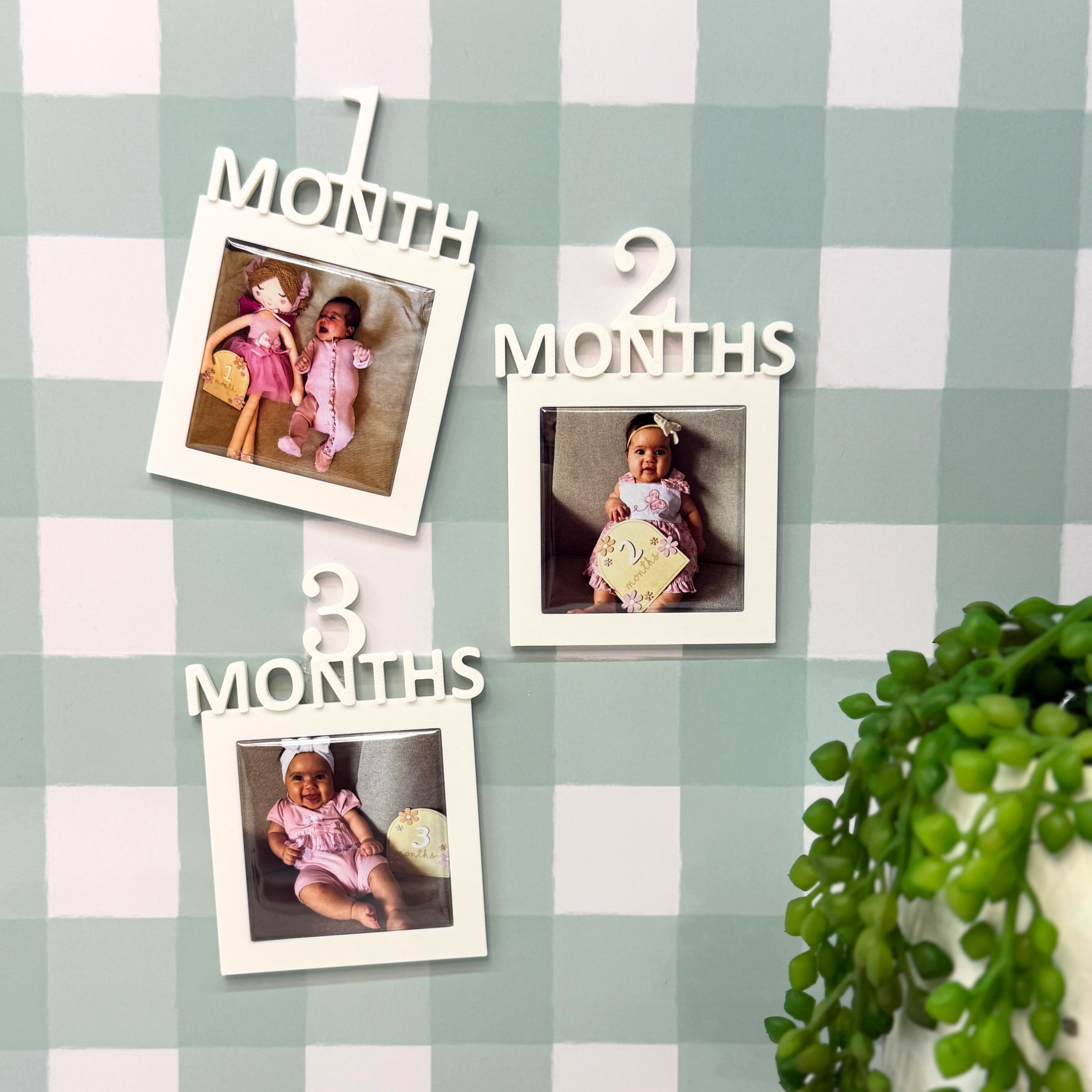 Three photo frames with baby milestone photos on a checkered wall.