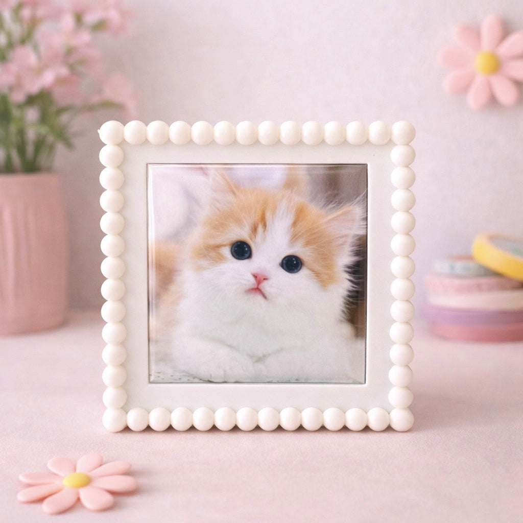 Framed picture of a cat with decorative flowers and items on a light pink background