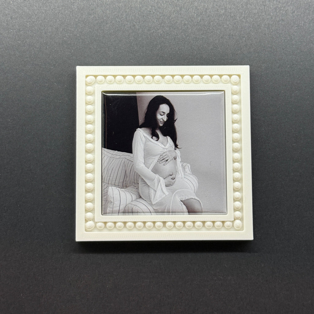 White decorative frame with a black and white photo of a couple on a dark gray wall.