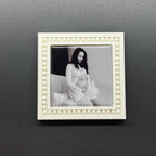 White decorative frame with a black and white photo of a couple on a dark gray wall.