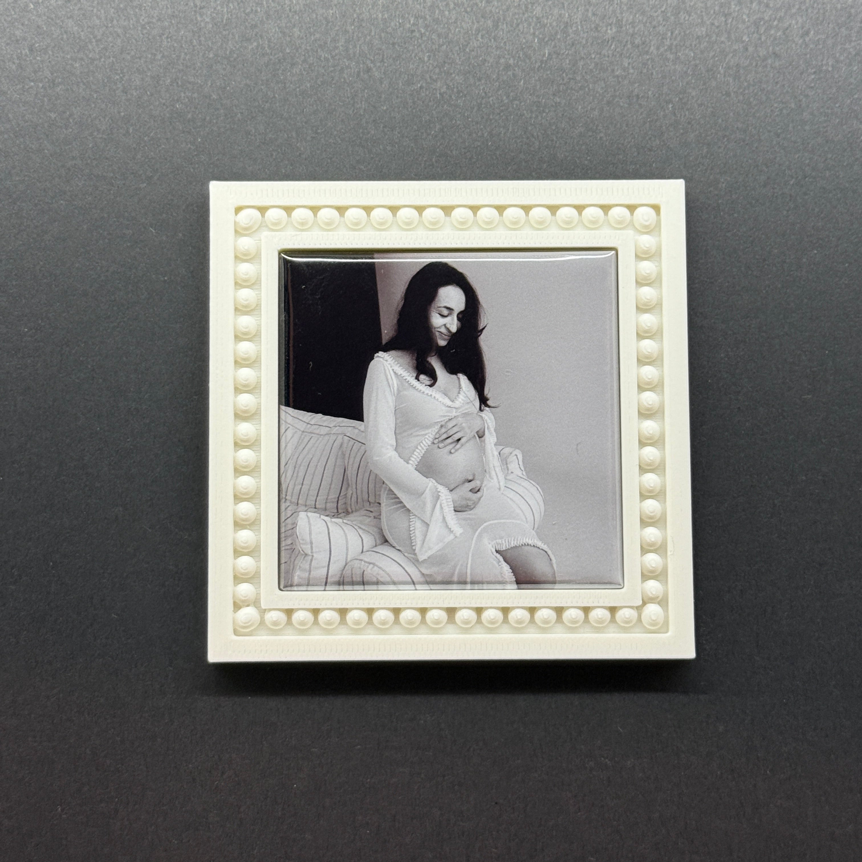 White decorative frame with a black and white photo of a couple on a dark gray wall.