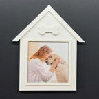 White house-shaped photo frame with a picture of a woman and dog on a dark background
