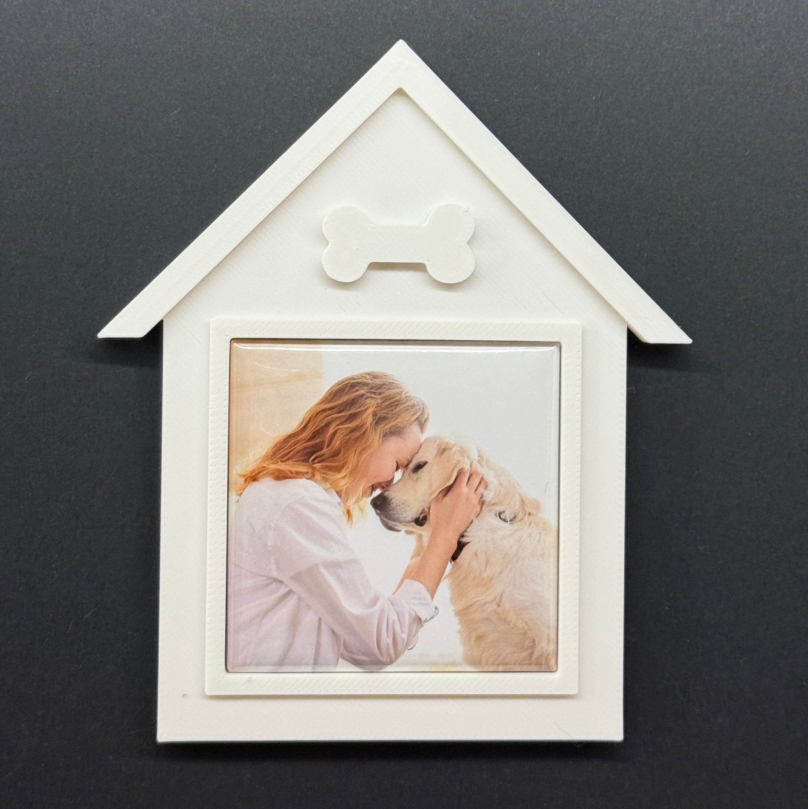 White house-shaped photo frame with a picture of a woman and dog on a dark background