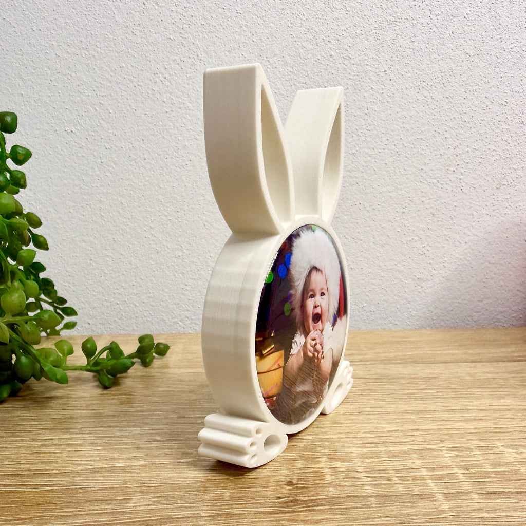 White bunny-shaped photo frame with a child's photo on a wooden surface.