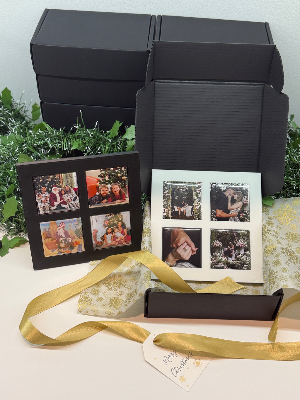 Black photo album with gold ribbon on a white surface with greenery in the background