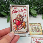 Hand holding a decorative hot chocolate bar packaging with festive design.
