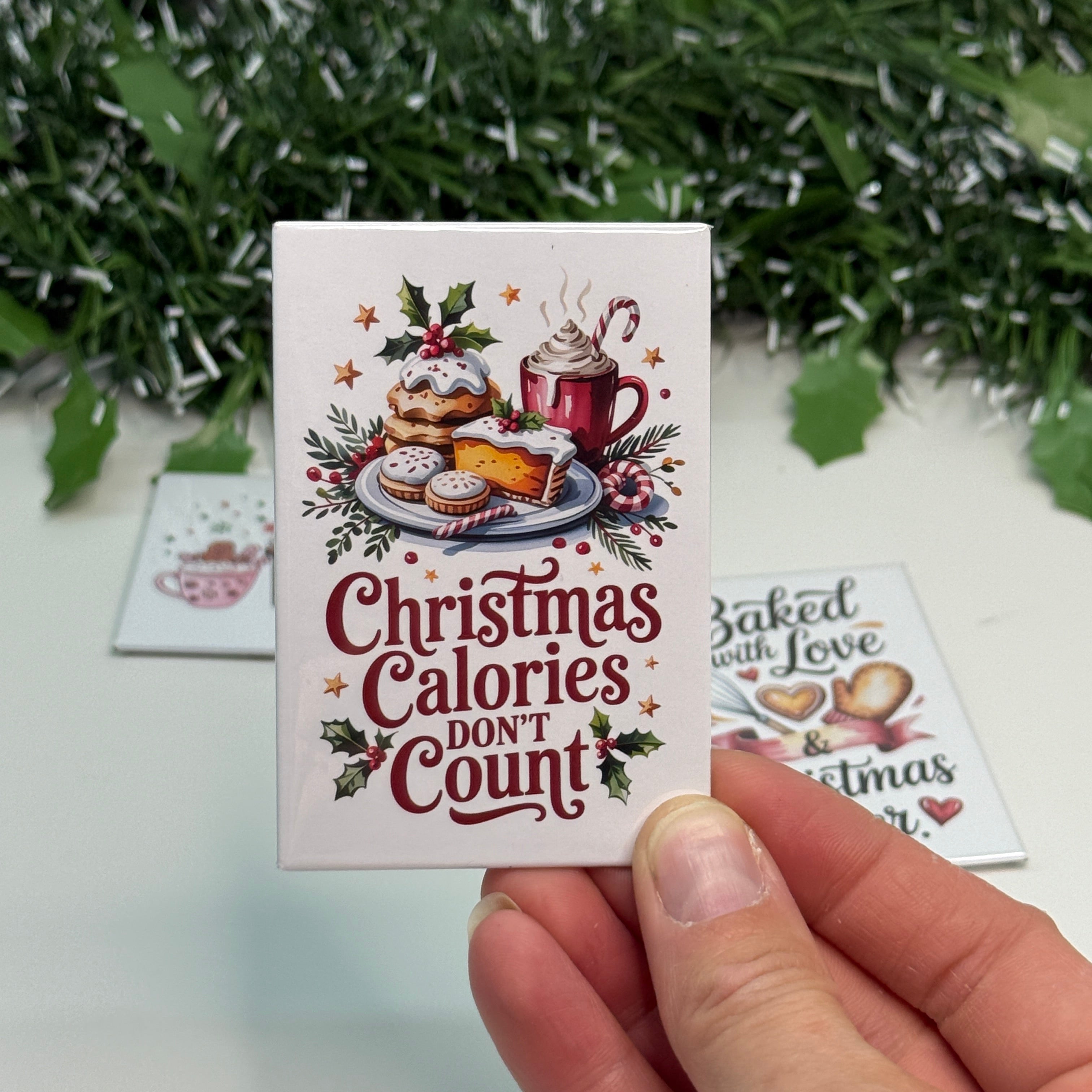 Hand holding a card with Christmas-themed text and graphics, with a decorative background.