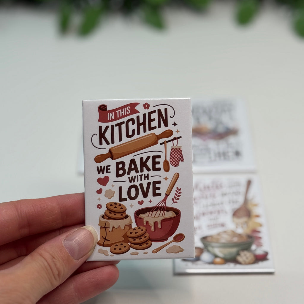 Card with 'In this kitchen we bake with love' text held by a hand on a light background