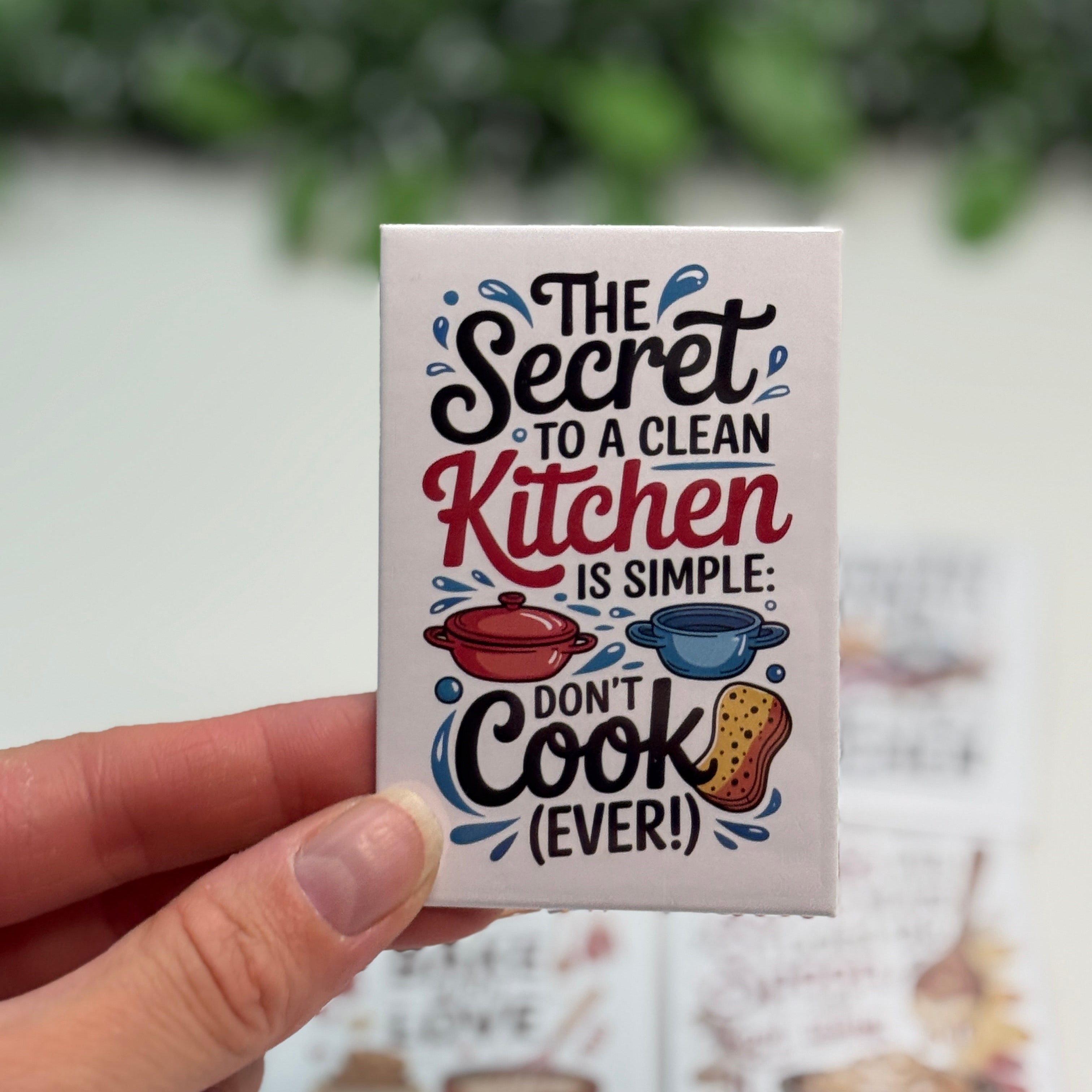 Small card with kitchen-themed text held by a hand against a blurred background
