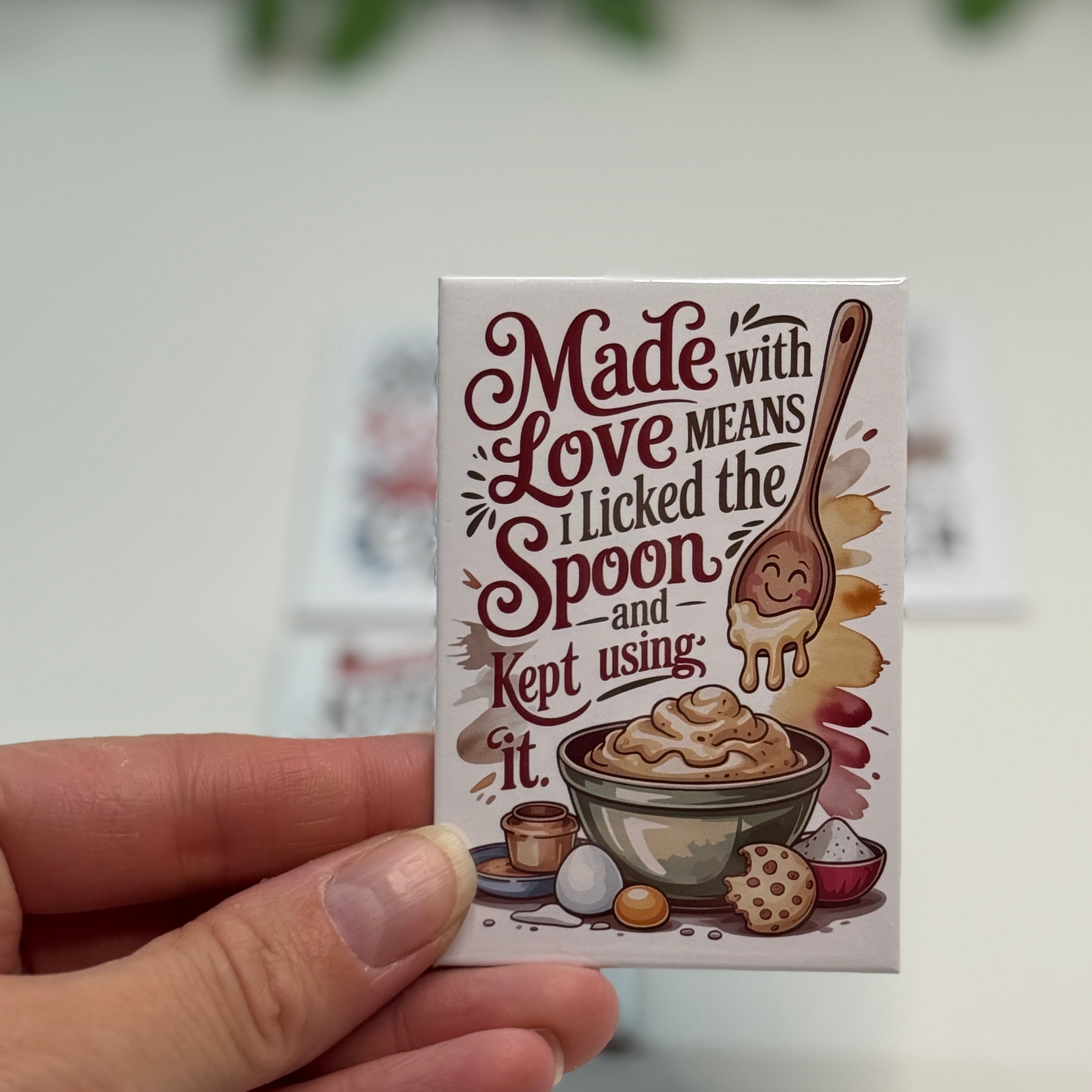 Small box with a decorative label held by a hand on a light background