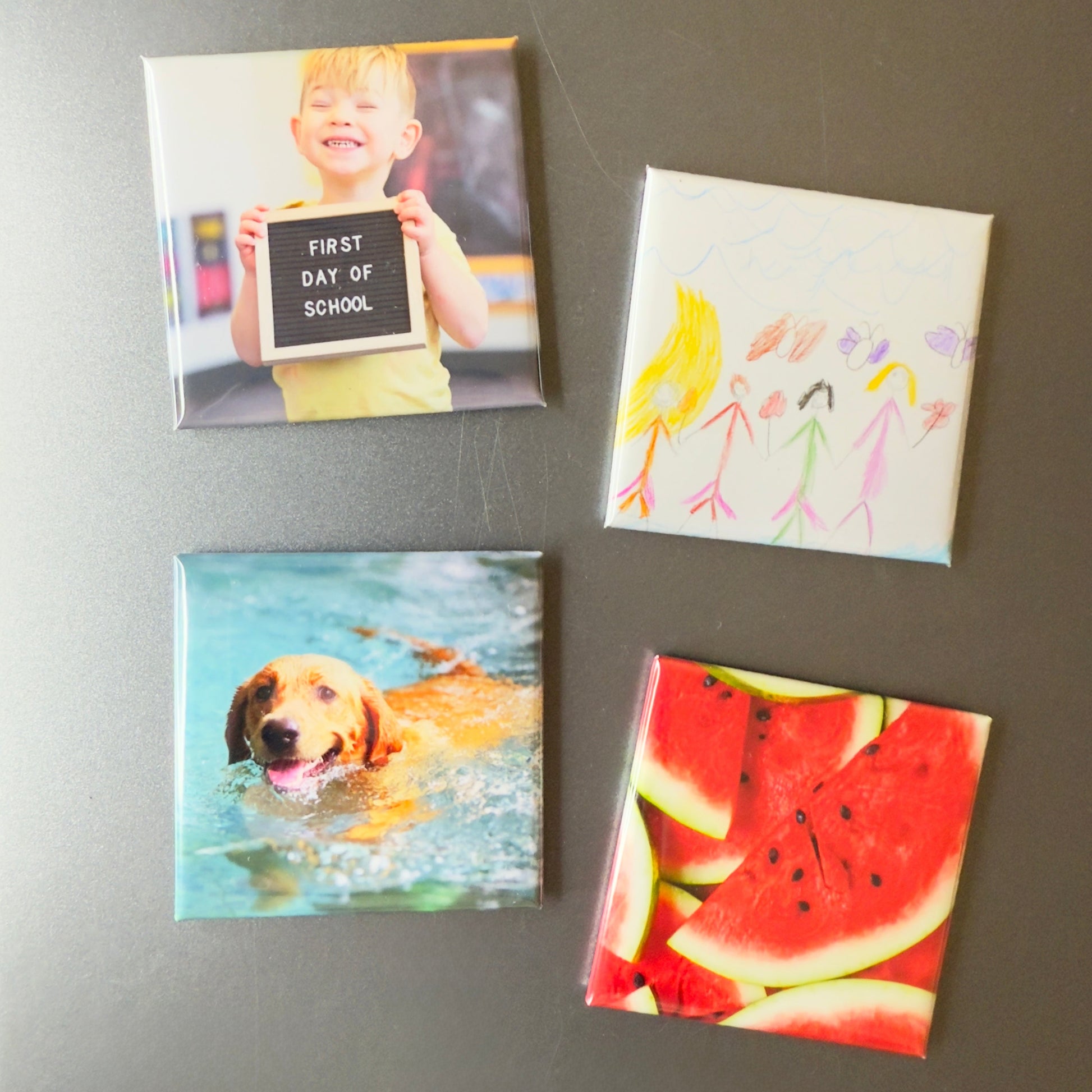 Four square magnets on a refrigerator with different images and text.