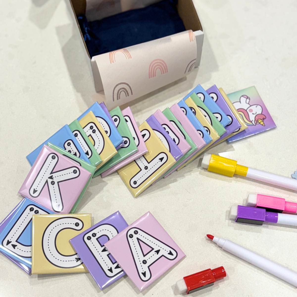 Colorful lettered sticky notes with markers on a light surface