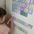 Child practising handwriting with Zara’s World pastel alphabet write and wipe magnetic tiles on a fridge, spelling out names with reusable letter magnets.